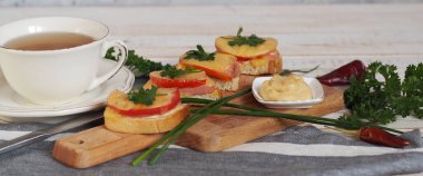 Sosisli, domatesli ve peynirli sıcak ev yapımı sandviçler. Doğal sağlıklı yiyecekler. Çay için ahşap arka planda sandviçler..