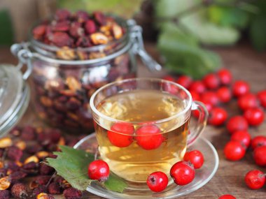 İleride kullanmak için kurumuş dikenleri topluyorum. Alternatif ilaç. Ahşap arka planda böğürtlenli bir fincan bitki çayı..