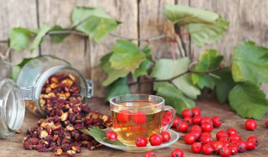 İleride kullanmak için kurumuş dikenleri topluyorum. Alternatif ilaç. Ahşap arka planda böğürtlenli bir fincan bitki çayı..