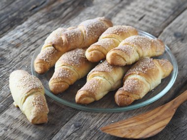 Eski bir ahşap zemine susam ve şeker serpiştirilmiş kruvasanlar. Ev yapımı kek..