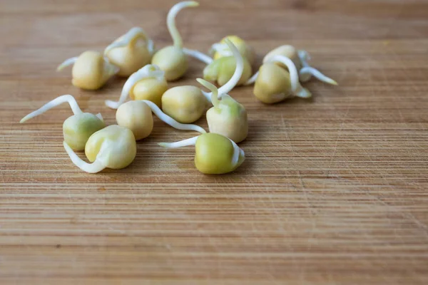 ビーガンや生の食べ物のための健康的な食品 木製の竹のまな板の上に発芽した甘いエンドウ豆の散乱ぼやけた背景で閉じます — ストック写真