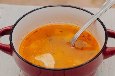 Domatesli basit sebze çorbası. Ekşi kremalı bir tabak köy çorbası ve tepesindeki tahta beyaz masada bir kaşık..