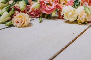 Kartpostal, duvar kağıdı ya da poster için bir buket pembe ve beyaz övgü. Tahtalardan yapılmış beyaz ahşap zemin üzerinde pastel renkte Eustoma çiçekleri metin için alan ile yakın plan perspektifinde.