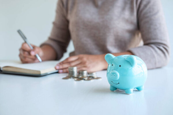 Young woman and piggy bank to planning growing saving strategy with pile coins for future plan fund of travel, education, home and retirement.