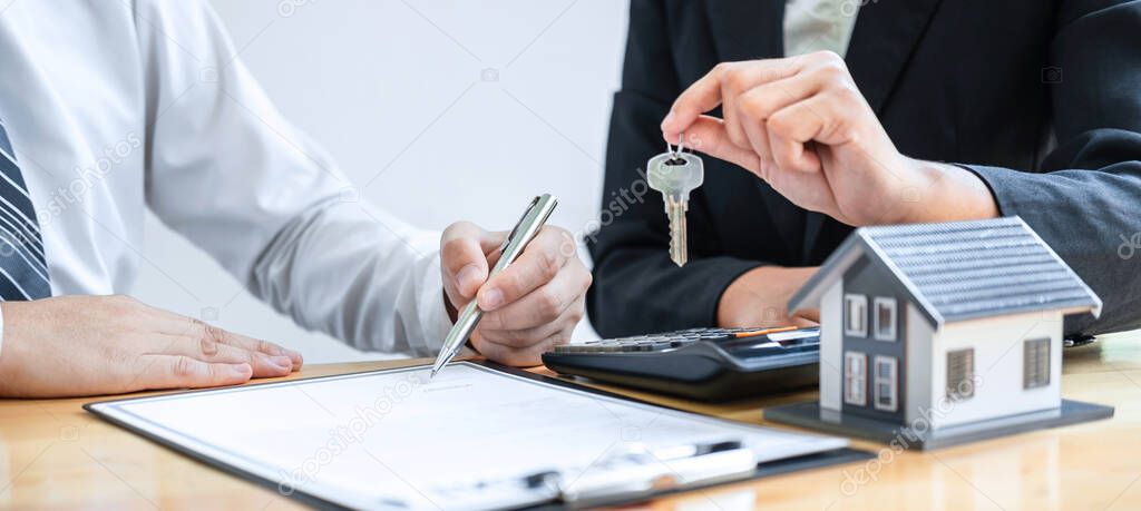 Home Insurance and Real estate investment concept, Sale agent giving house key to new client after signing agreement contract with approved property application form.