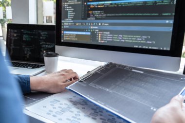 IT şirketinin ofisindeki yazılım geliştirme bilgisayarında proje üzerinde çalışan geliştirici programcısı, sorunlara çözüm bulmak için kodlar ve veri kodu web sitesi ve kodlama veritabanı teknolojileri.