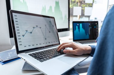 İşadamı yatırımcı borsacıların pazarlama, planlama ve analizinde çalışıyor ve hisse senedi verilerine işaret ediyor..