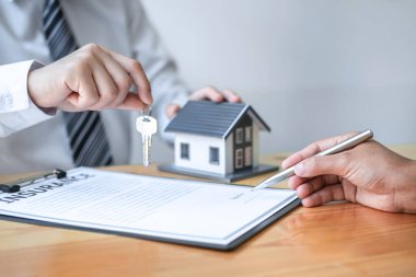 Ev Sigortası ve Gayrimenkul Yatırım Konsepti. Satış acentesinin yeni bir müşteriye ev anahtarı vermesi. Onaylanmış emlak başvuru formu ile anlaşma yaptıktan sonra..