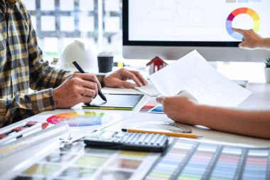 Modern ofiste çalışan grafik tablet ve renk örnekleri üzerine çizim yapan genç İç mimari çalışma evi projesinin takım tasarımı, yaratıcı ilham ve hayal gücü.