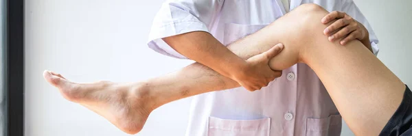 医生或理疗师检查运动员男性患者受伤腿的治疗情况 并在临床上进行康复治疗 — 图库照片