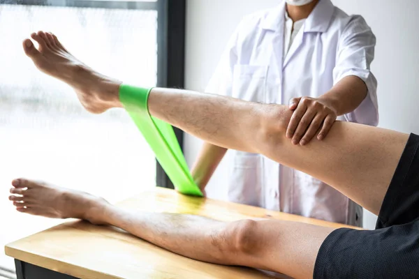 Doktor ya da fizyoterapist, yaralı erkek hasta bacağını tedavi ediyor, klinikte rehabilitasyon tedavisi uyguluyor..