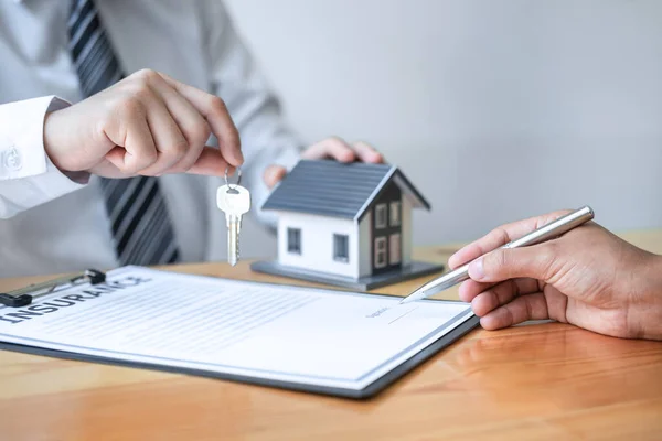 住宅保険と不動産投資の概念は 販売代理店は 承認された不動産申請書との契約を締結した後 新しいクライアントに家の鍵を与える — ストック写真