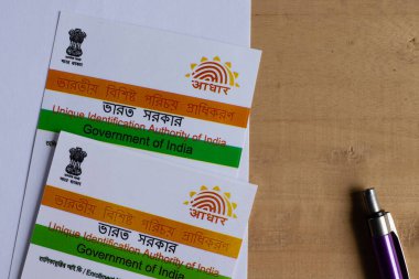 Birbhum, Batı Bengal / Hindistan - 18 Ağustos 2020: Hindistan 'ın Aadhaar kartları ve kahverengi ahşap masa üzerindeki kalem