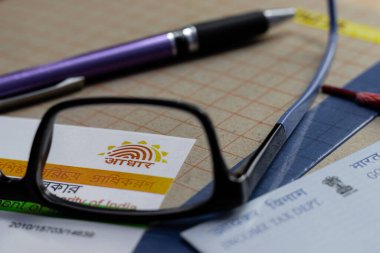 Birbhum, Batı Bengal / Hindistan - 18 Ağustos 2020: PAN ve kalem bulanık gözlüklerle Aadhaar sembolüne seçici odaklanma