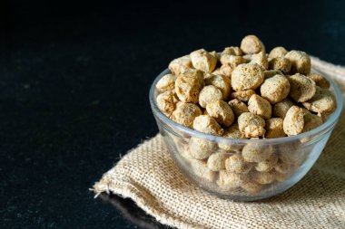 Siyah arka planda bir kase dolusu soya fasulyesi.