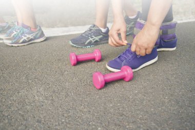 Seçici odak, tanınmayan kişiye yakın çekim. Dışarı çıkarken ayakkabı bağcıklarını sıkmak için eğilmiş.