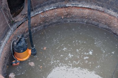 Kirli suyla dolu bir lağım çukuruna yakın çekim pompası dışkılar, ev atıkları pompalanması, insan kanalizasyonu, yakın çekim..