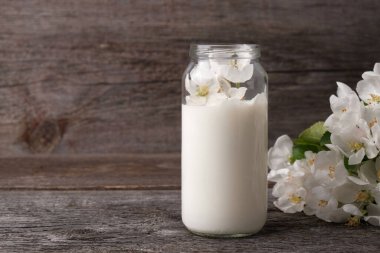 Elma ağacından elde edilen sütü cam bir kavanozda fotokopi alanı, doğal kozmetik konsepti, aromaterapi, bitkisel ilaç içeren ahşap arka planda saklıyorum..