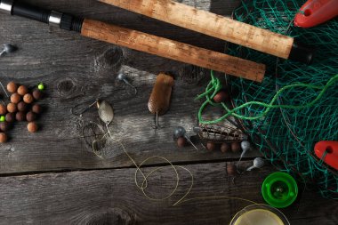 Fotokopi alanı olan eski bir ahşap arka planda balıkçılık malzemesi. Düz konum, olta, bobin, yem, yem, yem ve kafes.
