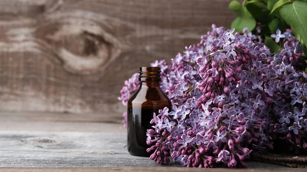 Lilac flower extract in  medical bottle on  wooden vintage background with copy space, the concept of natural cosmetics, body care, traditional medicine.