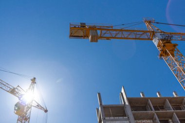 Mavi gökyüzünün arka planında vinçleri olan bir inşaat alanı. Yüksek binalar inşa etme kavramı.