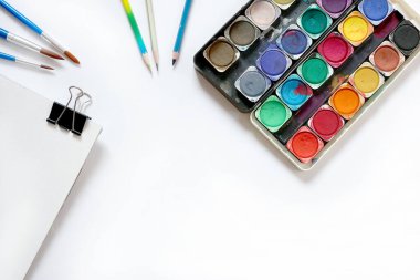 Suluboya boya kutusu ve beyaz arka planda fırçalar. Düz yatış, üst görünüm