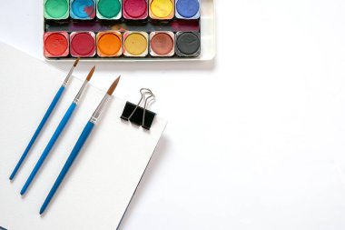Suluboya boya kutusu ve beyaz arka planda fırçalar. Düz yatış, üst görünüm