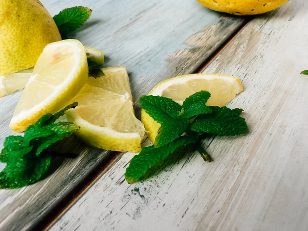 Fresh organic lemons and fresh mint leaves, peppermint on a rustic wooden table