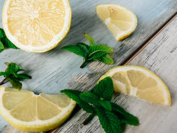 Fresh organic lemons and fresh mint leaves, peppermint on a rustic wooden table