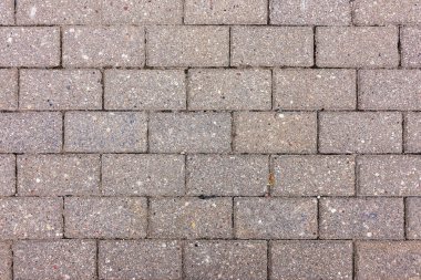 Bir yol üzerindeki beton blokların desenli düzenlenmesi. Güneş ışığı, şehir manzaraları veya yolları için ideal yüzey dokusunu vurgular.