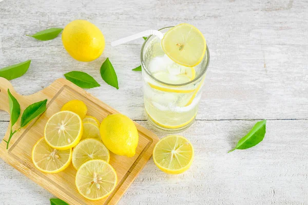 Beyaz ahşap bir masada limon suyu ve taze limon..
