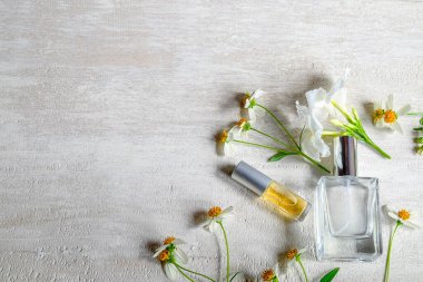 Parfüm şişesi ve beyaz arka planda yeşil yapraklı beyaz çiçek..