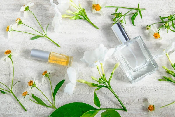 Parfüm şişesi ve beyaz arka planda yeşil yapraklı beyaz çiçek..