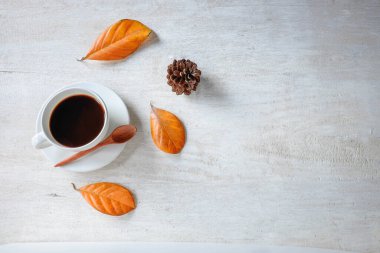 Çam kozalaklı ve yapraklı bir masada bir fincan kahve..