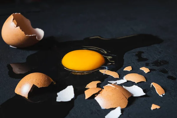 A cracked egg with an egg shell, egg yolk and egg