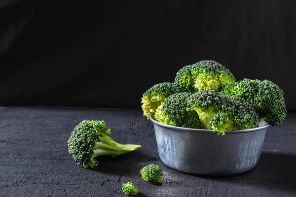 Broccoli in a bowl on a black background.