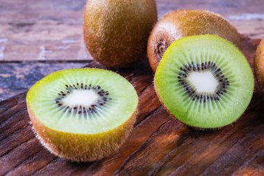 Tahta kesme tahtasıyla ikiye bölünmüş taze kiwifruit..