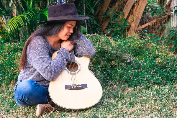 Genç hippi kadın bahçede gitar çalıyor.