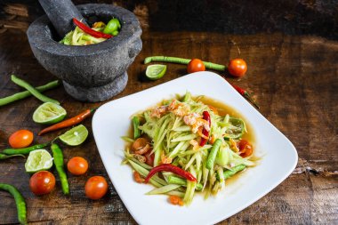 Tahta masada servis edilen bir tabakta Tayland yemeği, papaya salatası ve papaya salatası pişirmek..