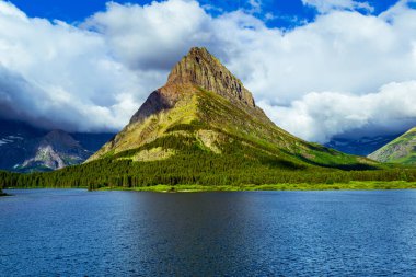 Swiftcurrent Gölü 'nde 5043 Bulutlu bir sabah Grinnell Point ile Montana Buzul Ulusal Parkı' nda Sunshine 'da yıkandı.