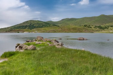 Dağların, göllerin ve bulutlu gökyüzünün manzarası