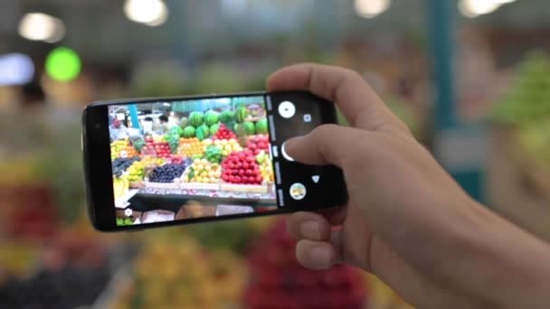 男は携帯電話で地元の市場で果物や野菜の写真を撮る — ストック動画