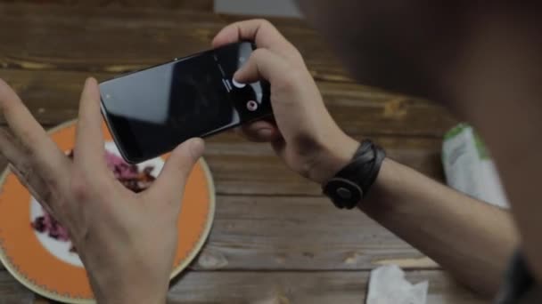 El hombre toma una foto del plato que puso en el cuenco de la mesa con su teléfono — Vídeo de stock