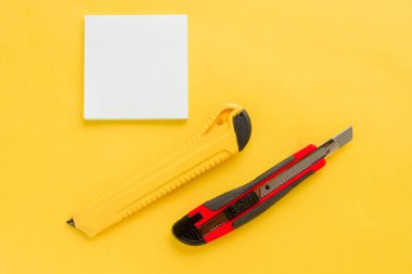 Beyaz kare notlar, sarı ve kırmızı ofis bıçağı.