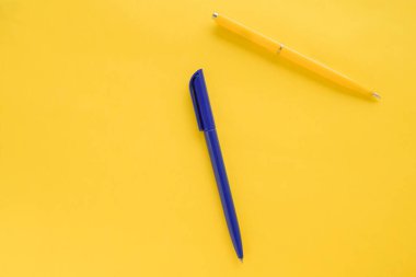 Sarı arka planda sarı ve mavi kalem. Üst Manzara. Minimalizm. Geçmişi temiz görünüyor. Düz yatıyordu. Kopyalama alanı ile şablon. İki kalem. Konsept başbakanlık, ofis malzemeleri, aksesuarlar