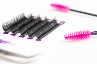 Bir güzellik salonunda kirpik uzatma için ayrı kirpikleri var. Beyaz arka planda kirpik uzatma işlemi için ayarlandı. tam teşekküllü makyaj için melez kirpik uzantıları.
