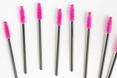 Beyaz arka planda kirpikleri ve kaşları için kozmetik fırçalar. Kirpik uzantıları için pembe taraklar. Üst görünüm.