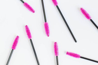 Beyaz arka planda kirpikleri ve kaşları için kozmetik fırçalar. Kirpik uzantıları için pembe taraklar. Üst görünüm.