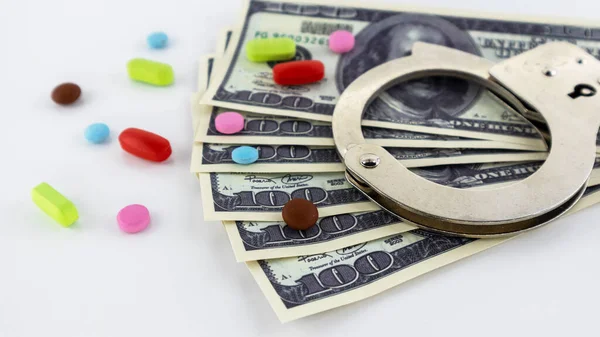 Metal handcuffs with money and pills on a white background — Stock Photo, Image