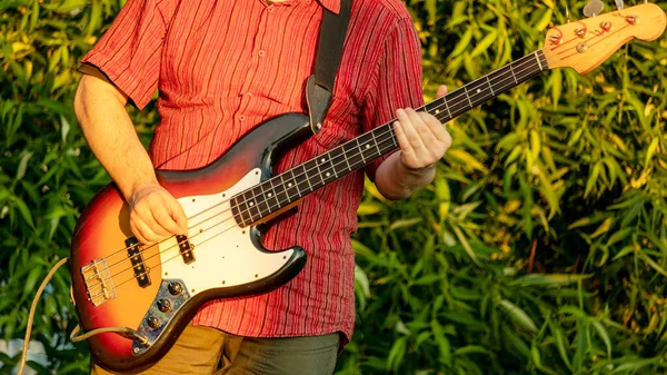 A man playing bass guitar in a Park — Stock Photo, Image